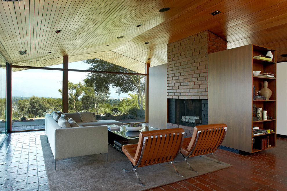 Cette photo montre un salon rétro ouvert avec une cheminée standard, un manteau de cheminée en brique, un sol rouge, un plafond voûté et un plafond en bois.