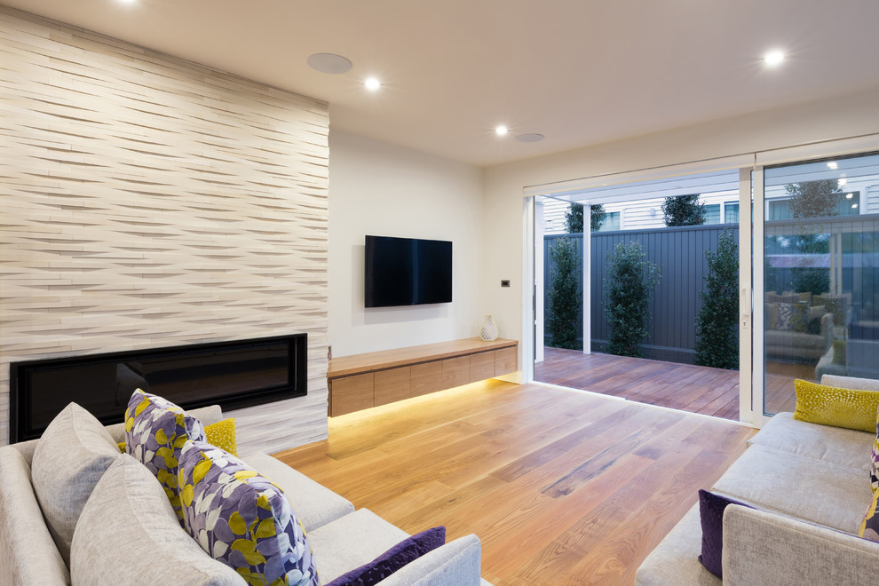 Foto de salón abierto contemporáneo grande con paredes blancas, suelo de madera clara, chimenea lineal, marco de chimenea de ladrillo y televisor colgado en la pared