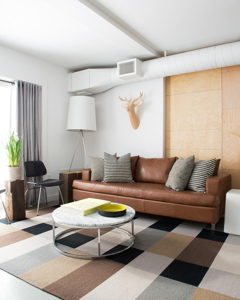 На фото: гостиная комната в стиле лофт с белыми стенами и коричневым диваном с