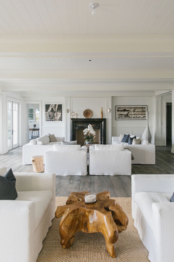 Photo of an expansive beach style formal open plan living room in Los Angeles with white walls, plywood flooring, a standard fireplace, a stone fireplace surround and white floors.