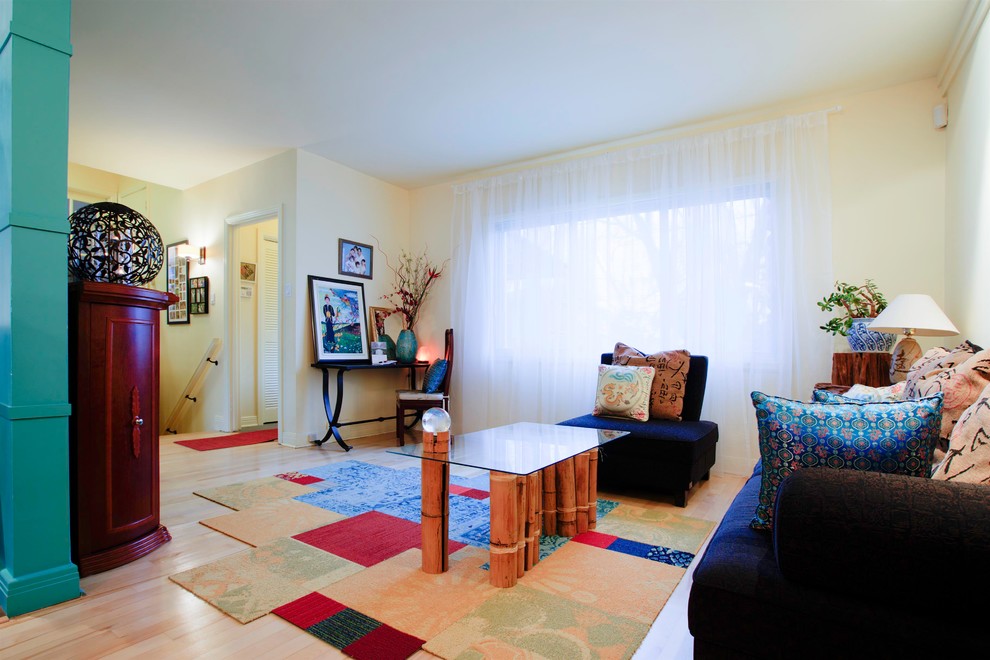 Fernseherloses Asiatisches Wohnzimmer mit gelber Wandfarbe, hellem Holzboden, Kamin und Kaminumrandung aus Metall in Montreal