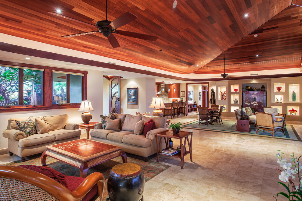 Foto di un ampio soggiorno tropicale aperto con pareti beige, pavimento in travertino e TV nascosta