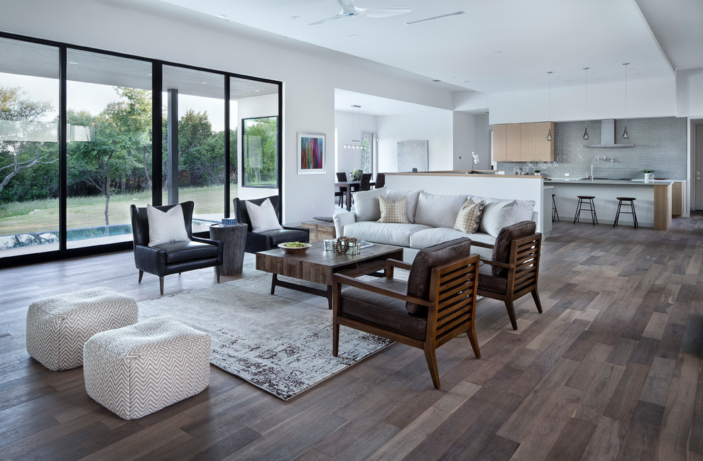 Example of a large trendy formal and open concept medium tone wood floor and brown floor living room design in Austin with white walls, a ribbon fireplace, a plaster fireplace and no tv