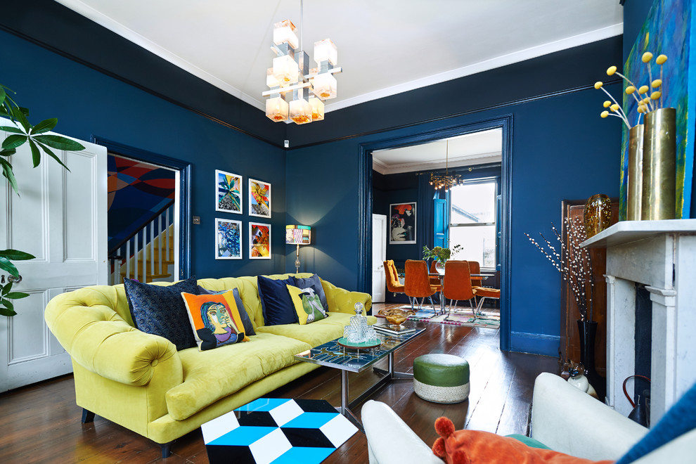 Bild på ett stort funkis separat vardagsrum, med ett finrum, blå väggar, mörkt trägolv, en standard öppen spis, en spiselkrans i sten och en dold TV