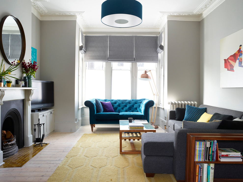 Classic formal and grey and teal enclosed living room in London with grey walls, light hardwood flooring, a standard fireplace, a metal fireplace surround, a freestanding tv and beige floors.