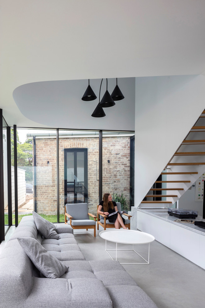 Offenes Modernes Wohnzimmer ohne Kamin mit weißer Wandfarbe, Betonboden und grauem Boden in Sydney