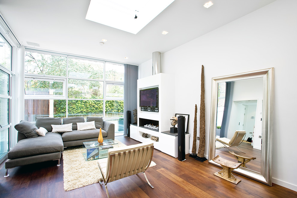 Cette image montre un salon design de taille moyenne avec un mur blanc, parquet foncé, un téléviseur encastré, un sol marron et une cheminée ribbon.