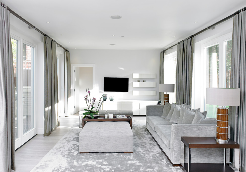 На фото: гостиная комната в стиле неоклассика (современная классика) с телевизором на стене и красивыми шторами с