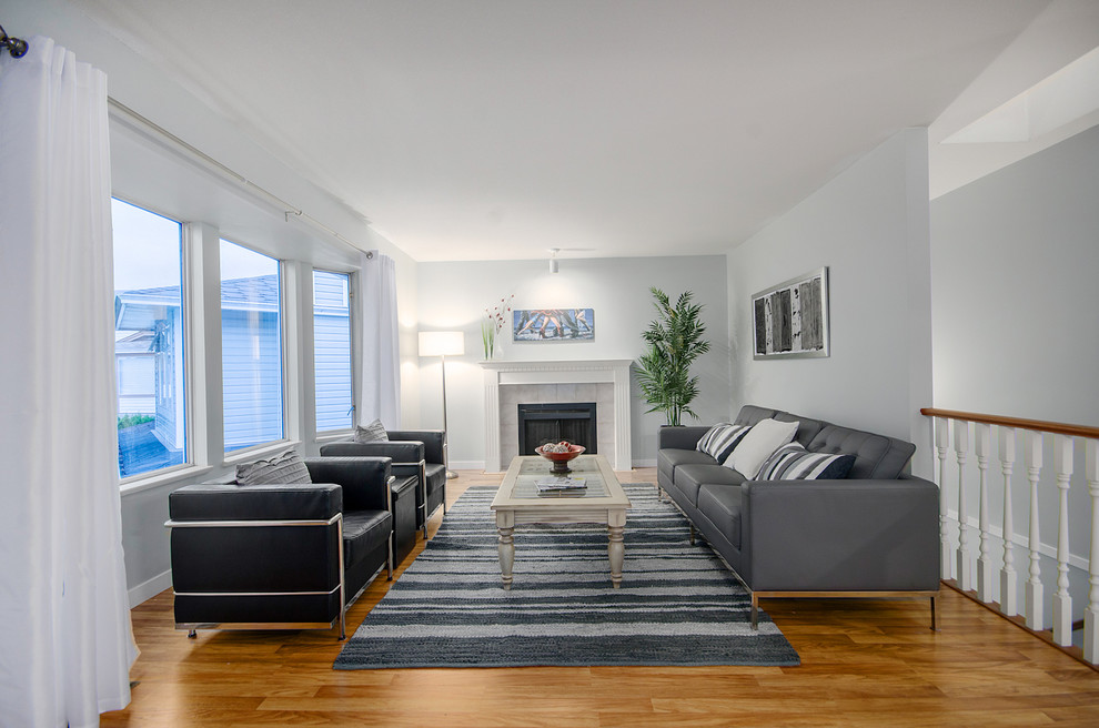 Großes, Abgetrenntes Modernes Wohnzimmer mit grauer Wandfarbe, braunem Holzboden, Kamin und gefliester Kaminumrandung in Vancouver