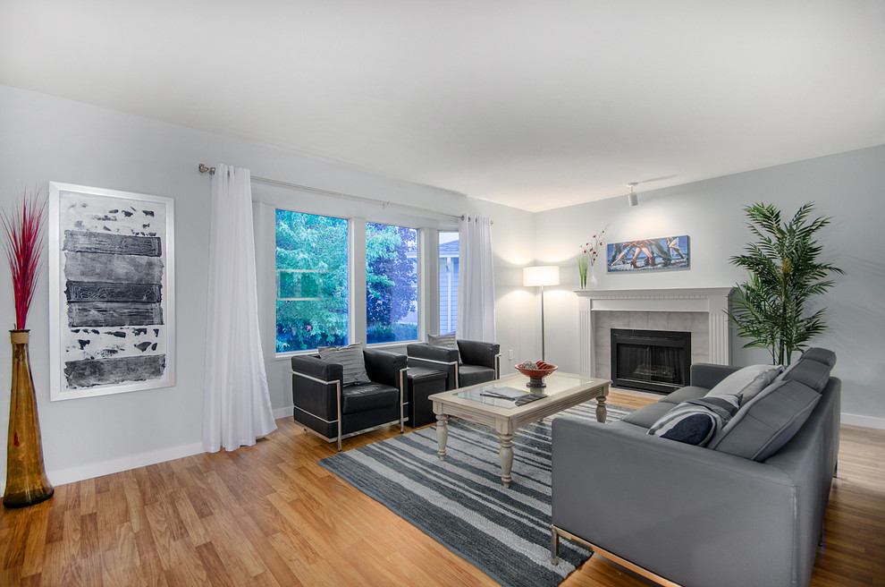 This is an example of a large contemporary enclosed living room in Vancouver with grey walls, medium hardwood flooring, a standard fireplace and a tiled fireplace surround.