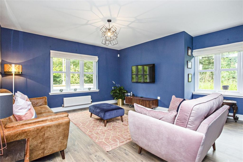 Idée de décoration pour un salon vintage de taille moyenne et fermé avec un mur bleu, sol en stratifié, aucune cheminée, un téléviseur fixé au mur et un sol marron.