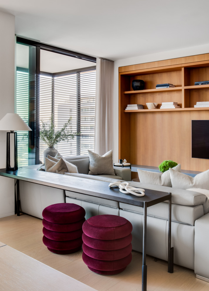Пример оригинального дизайна: большая открытая гостиная комната в современном стиле с белыми стенами, светлым паркетным полом, телевизором на стене и бежевым полом