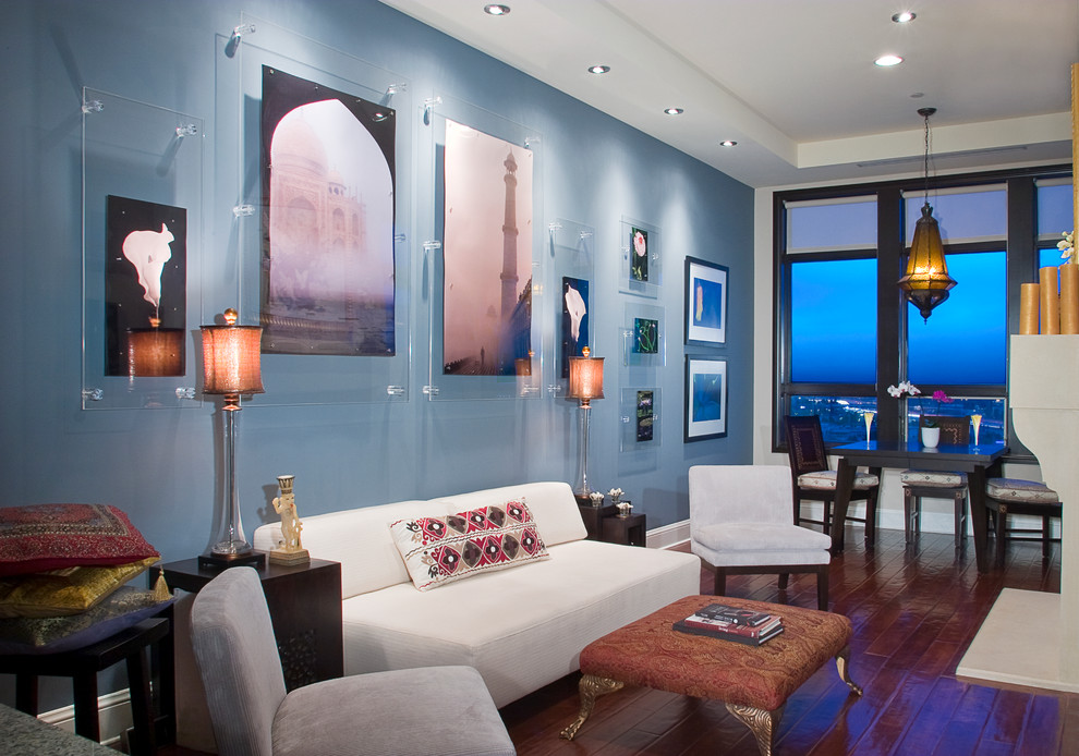 Réalisation d'un grand salon design ouvert avec un mur bleu, parquet foncé, une cheminée standard, un manteau de cheminée en pierre, un téléviseur dissimulé et un sol marron.