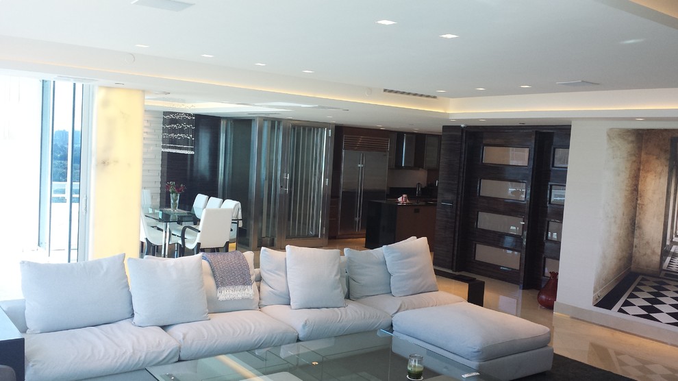 Imagen de salón abierto contemporáneo grande con paredes beige, suelo de mármol y televisor colgado en la pared