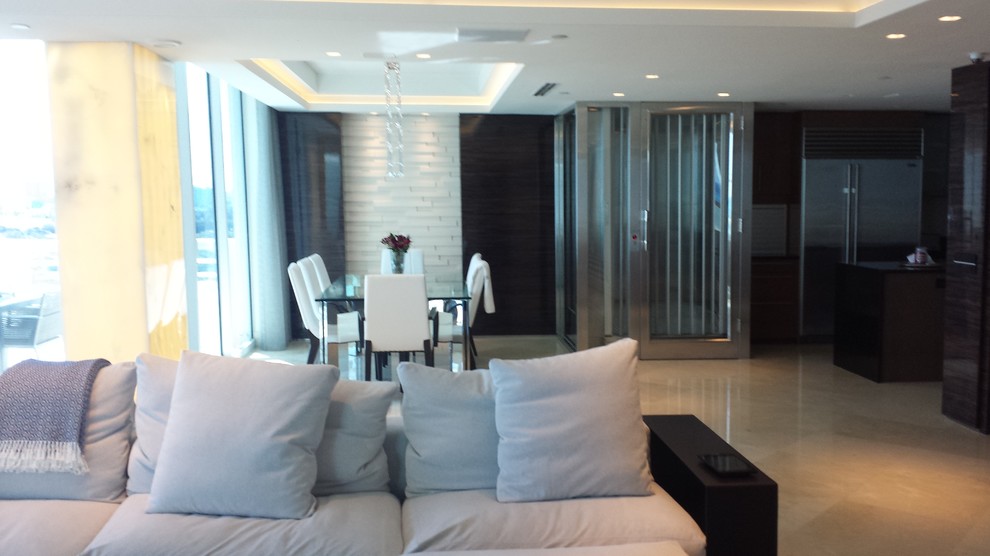 Modelo de salón abierto contemporáneo grande con paredes beige, suelo de mármol y televisor colgado en la pared