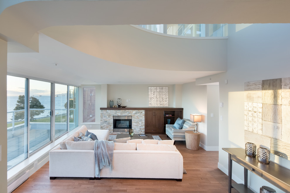 Großes, Offenes Modernes Wohnzimmer mit beiger Wandfarbe, braunem Holzboden, Kamin und Kaminumrandung aus Stein