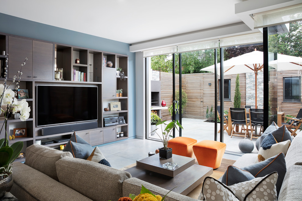 Стильный дизайн: гостиная комната в современном стиле с синими стенами, телевизором на стене и серым полом - последний тренд