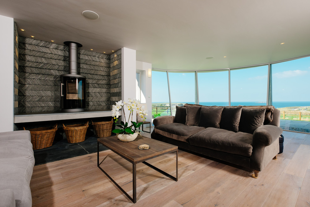 Стильный дизайн: парадная гостиная комната в морском стиле с печью-буржуйкой, белыми стенами, паркетным полом среднего тона и коричневым диваном - последний тренд