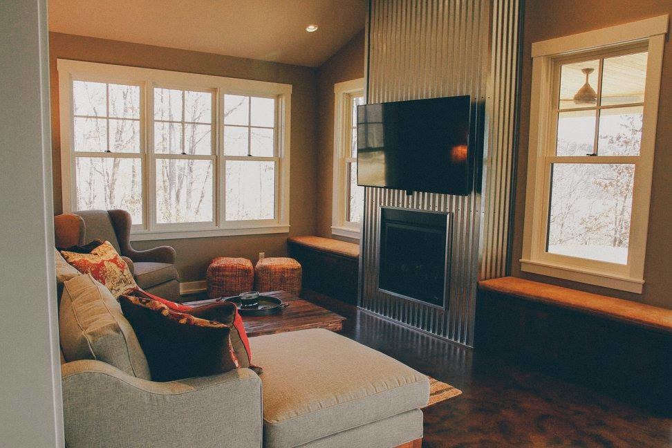 Mittelgroßes, Offenes Landhaus Wohnzimmer mit Betonboden, Kamin, Kaminumrandung aus Metall, beiger Wandfarbe und TV-Wand in Minneapolis