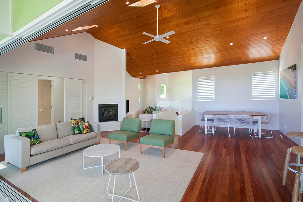 Großes, Offenes Maritimes Wohnzimmer mit weißer Wandfarbe, braunem Holzboden, Eckkamin, Kaminumrandung aus Holz und freistehendem TV in Sunshine Coast