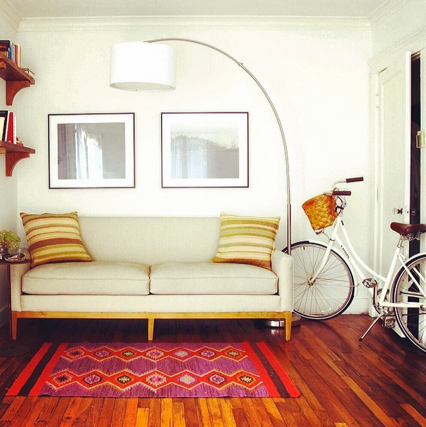 Immagine di un piccolo soggiorno minimalista chiuso con pareti bianche, pavimento in legno massello medio, nessun camino e pavimento marrone