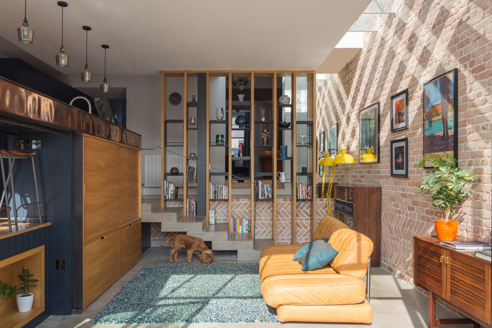 Ispirazione per un piccolo soggiorno design aperto con pareti rosse, TV nascosta, pavimento grigio e pareti in mattoni