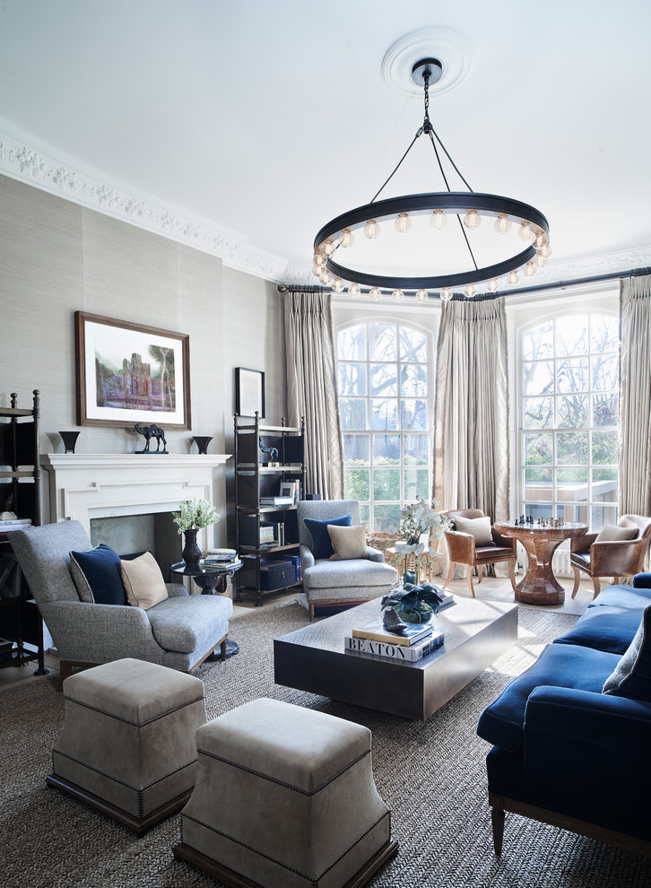На фото: большая парадная гостиная комната в стиле неоклассика (современная классика) с серыми стенами, стандартным камином, синим диваном и ковром на полу без телевизора с