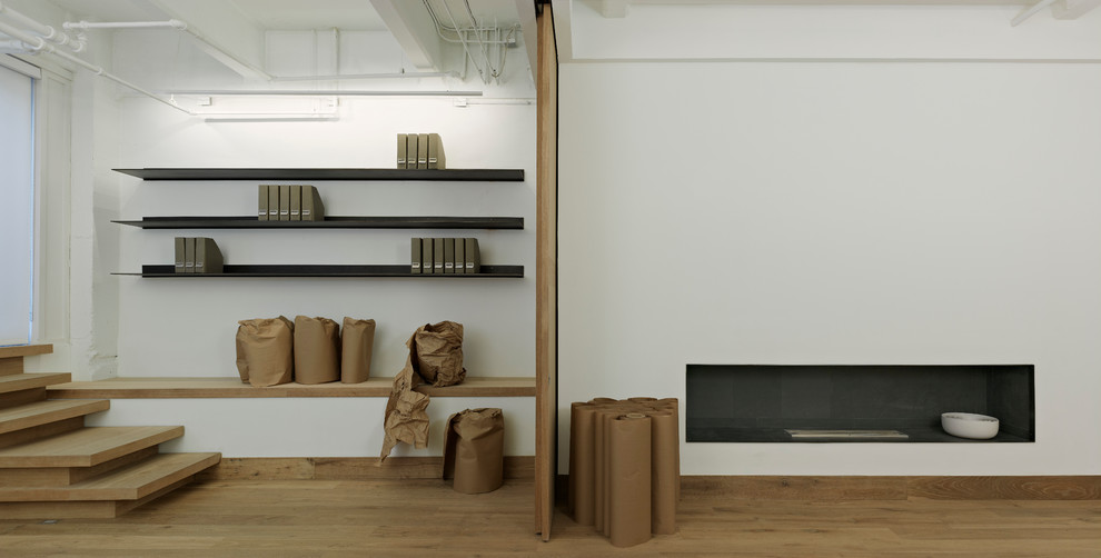 Diseño de salón tipo loft minimalista con paredes blancas y suelo de madera clara