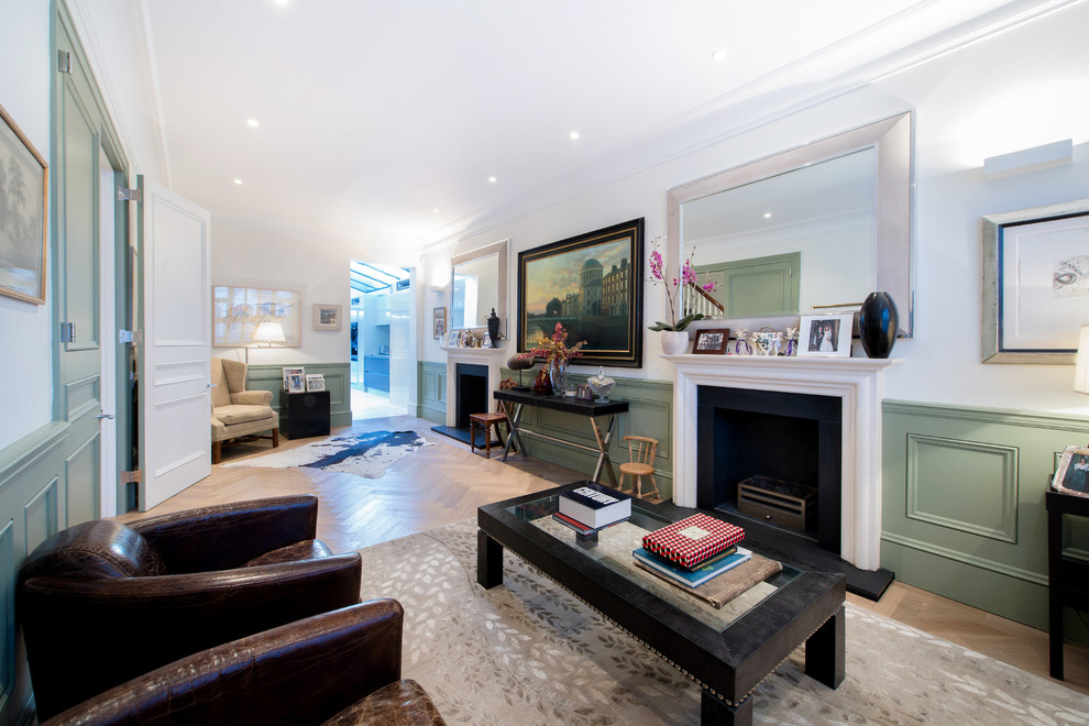 This is an example of a traditional formal open plan living room in London with white walls, light hardwood flooring, a standard fireplace and no tv.