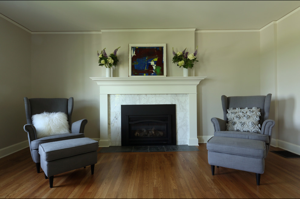 Пример оригинального дизайна: маленькая изолированная гостиная комната в стиле неоклассика (современная классика) с серыми стенами, паркетным полом среднего тона, стандартным камином, фасадом камина из дерева и отдельно стоящим телевизором для на участке и в саду