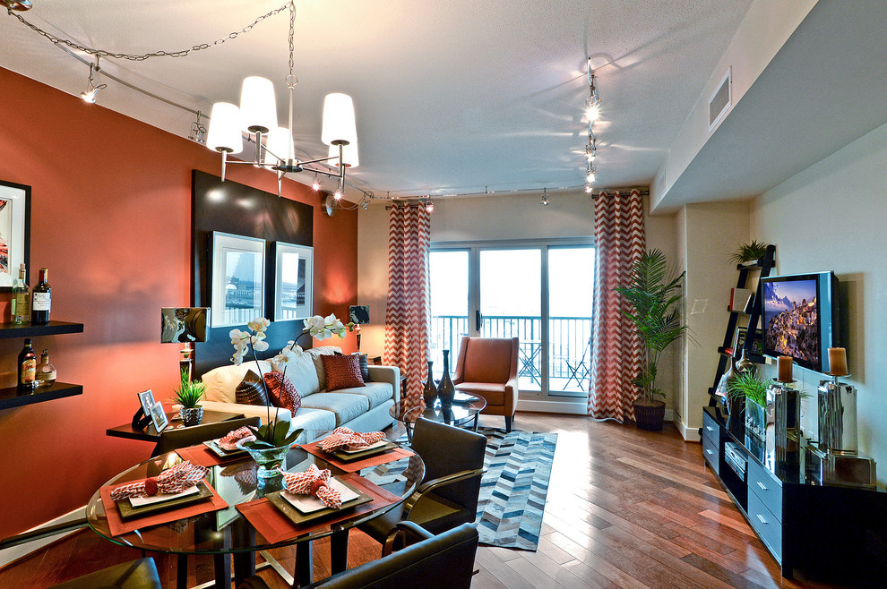 Источник вдохновения для домашнего уюта: маленькая открытая гостиная комната в современном стиле с оранжевыми стенами, паркетным полом среднего тона и телевизором на стене для на участке и в саду
