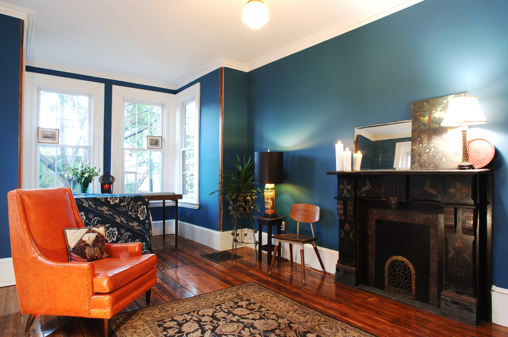 Idee per un soggiorno bohémian di medie dimensioni e aperto con pareti blu, pavimento in legno massello medio e cornice del camino in pietra
