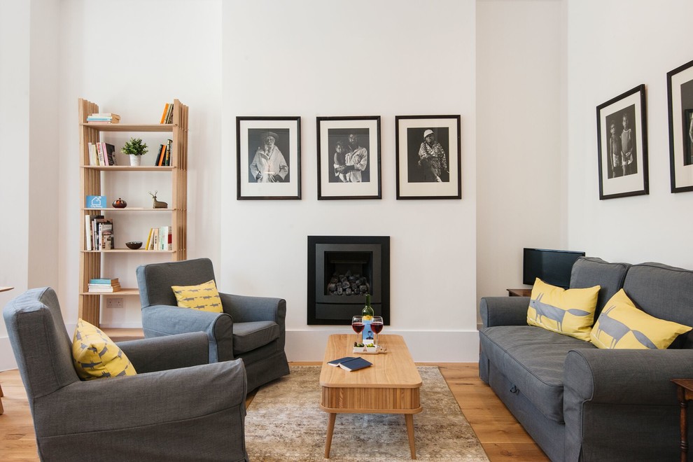 Esempio di un soggiorno minimal chiuso con pareti bianche, parquet chiaro, camino classico e pavimento beige