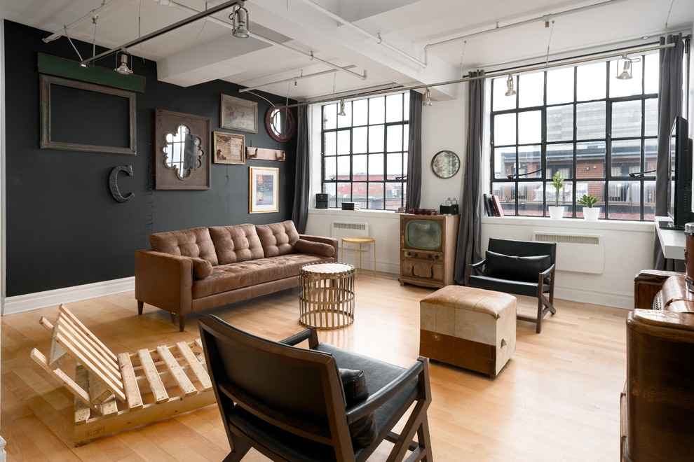 Diseño de salón industrial con paredes negras, suelo de madera en tonos medios y televisor independiente