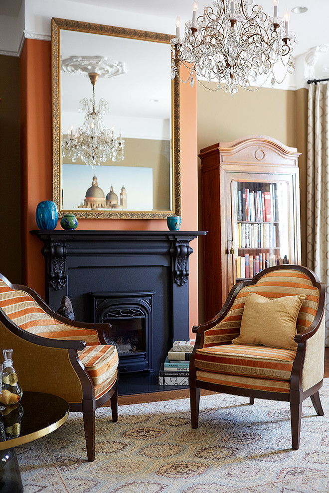 Idée de décoration pour un grand salon avec un mur orange et une cheminée standard.