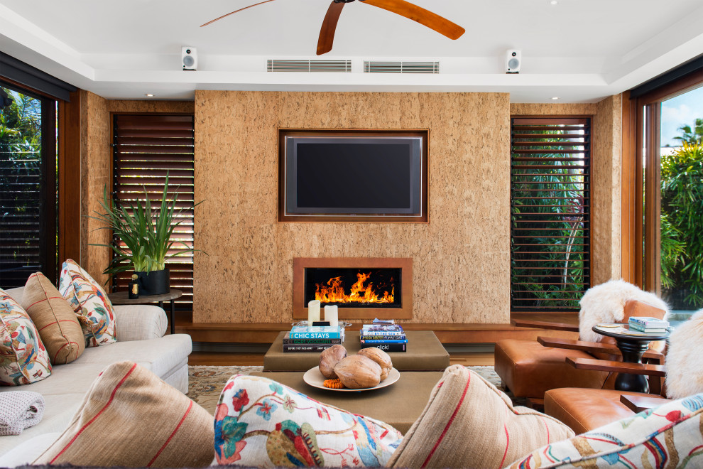 Modelo de salón exótico con paredes marrones, suelo de madera en tonos medios, chimenea lineal, televisor colgado en la pared y suelo marrón