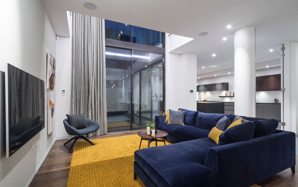 Trendy formal and open concept medium tone wood floor living room photo in London with white walls and a wall-mounted tv