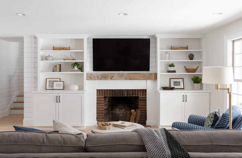 ボストンにあるお手頃価格の中くらいなカントリー風のおしゃれなLDK (白い壁、淡色無垢フローリング、標準型暖炉、レンガの暖炉まわり、壁掛け型テレビ、ベージュの床) の写真