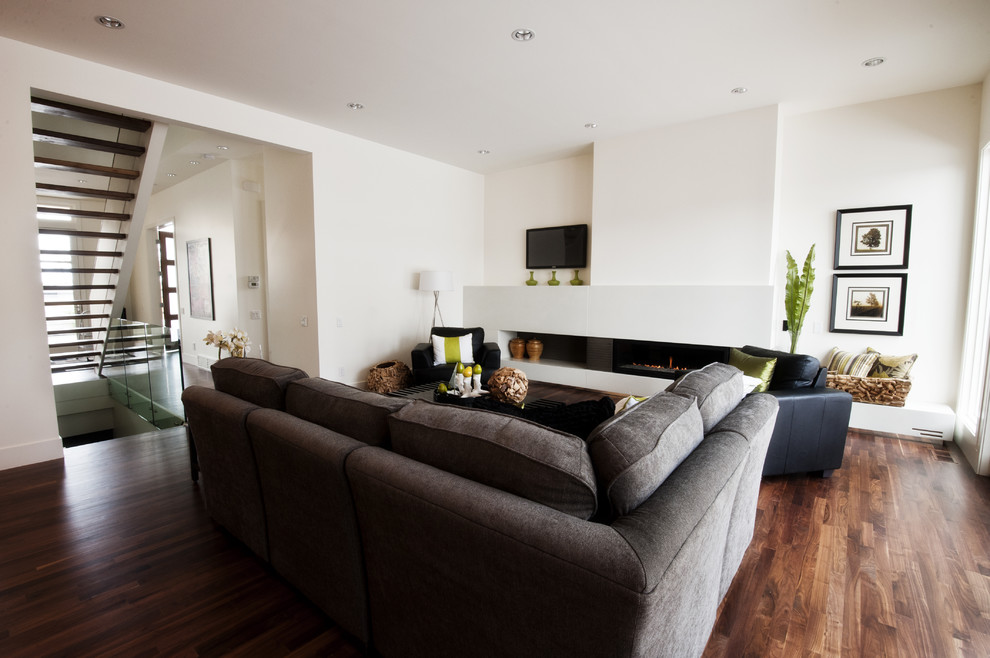 На фото: большая гостиная комната в современном стиле с белыми стенами, горизонтальным камином и телевизором на стене с