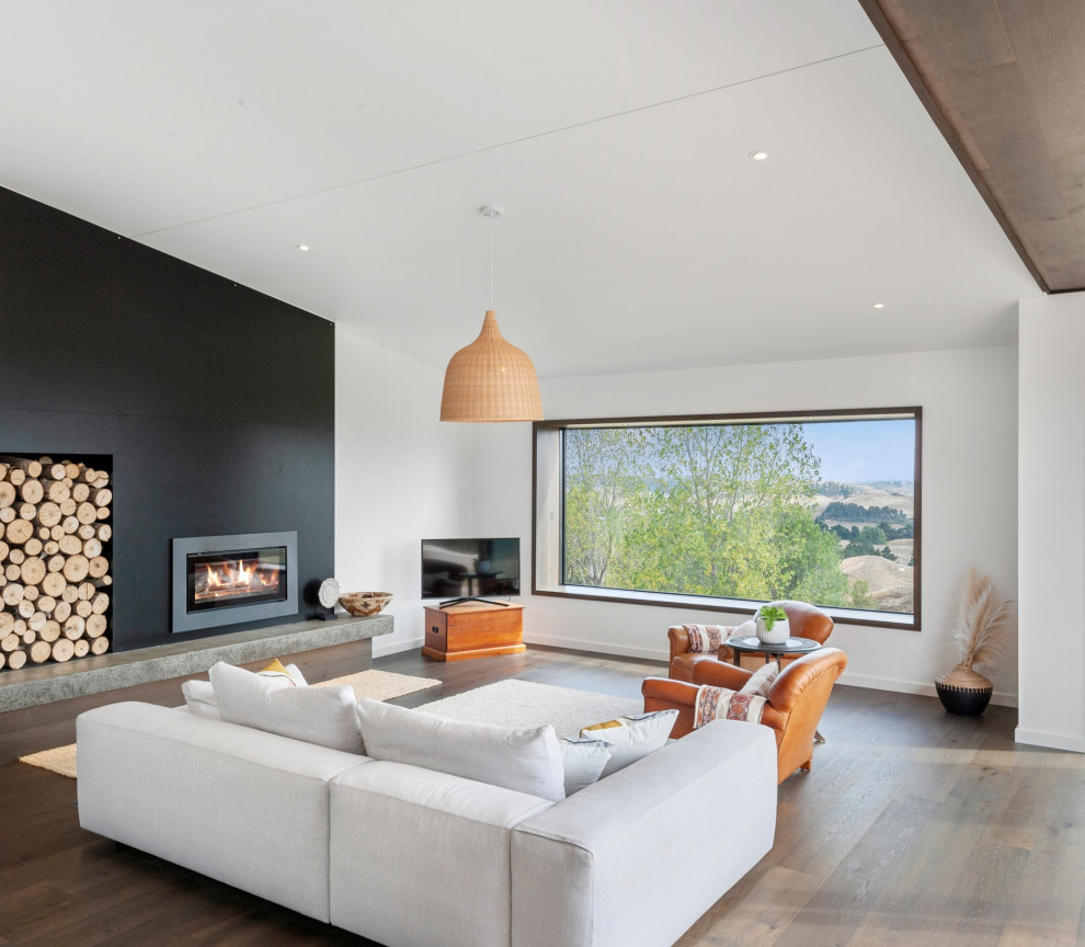 Inspiration pour un salon design de taille moyenne et ouvert avec un mur blanc, un sol en bois brun, un poêle à bois, un manteau de cheminée en métal, un téléviseur indépendant, un sol marron et un plafond voûté.