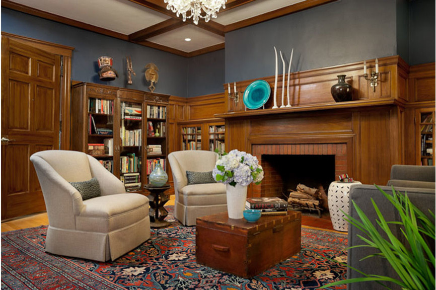 Klassisk inredning av ett mellanstort separat vardagsrum, med blå väggar, ljust trägolv, en standard öppen spis, en spiselkrans i tegelsten och ett bibliotek
