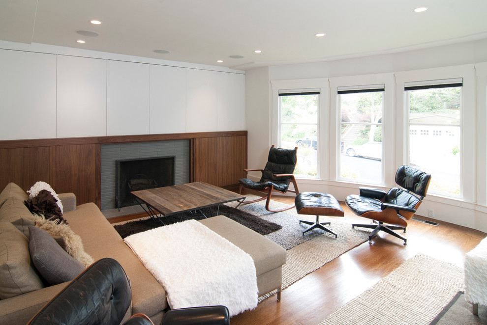 Inspiration for a mid-sized contemporary formal and enclosed medium tone wood floor living room remodel in San Francisco with white walls, a standard fireplace, a brick fireplace and a concealed tv