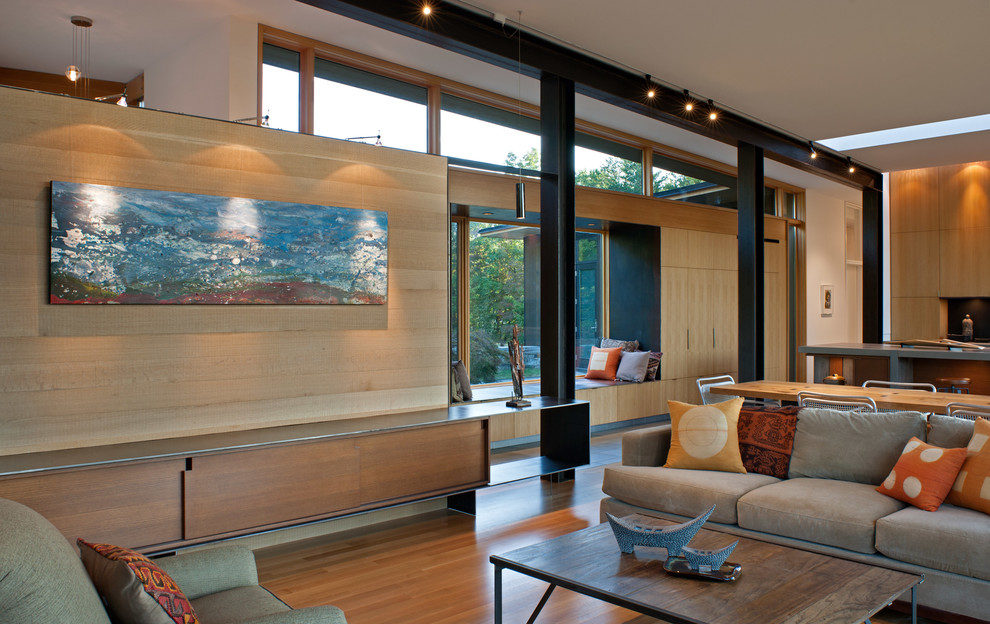 На фото: открытая гостиная комната в стиле модернизм с бежевыми стенами, светлым паркетным полом, стандартным камином, фасадом камина из дерева и бежевым полом с