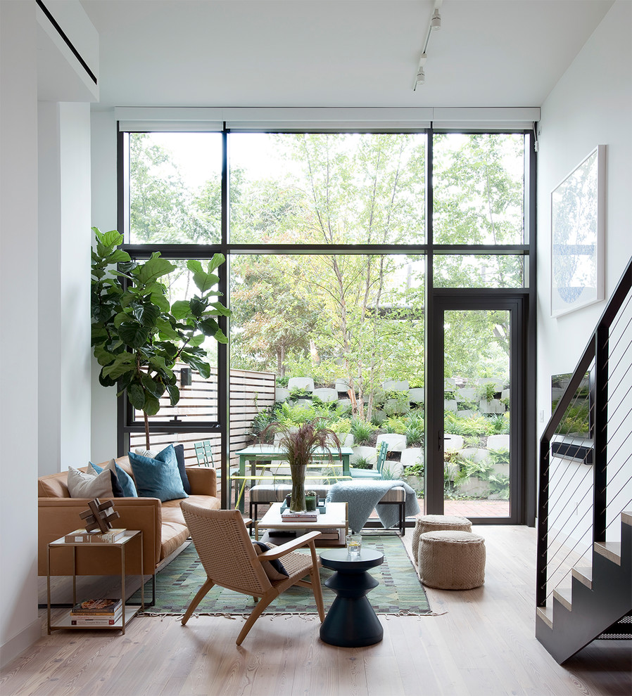 This is an example of a contemporary living room in New York with white walls and light hardwood flooring.