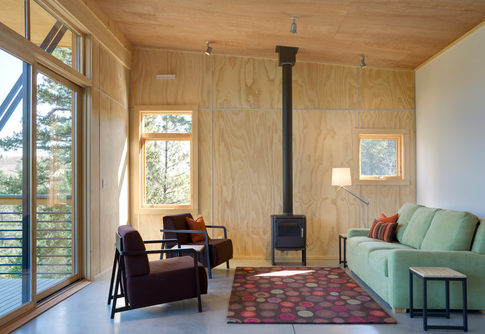 Cette image montre un salon minimaliste avec sol en béton ciré et un poêle à bois.