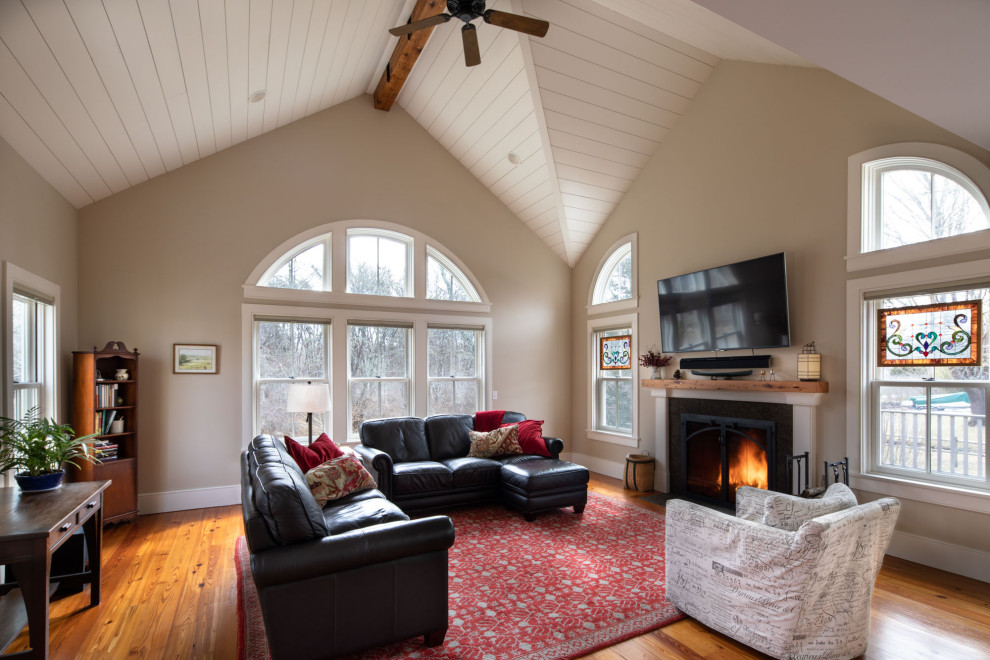 Mittelgroßes, Offenes Klassisches Wohnzimmer mit beiger Wandfarbe, Kamin, TV-Wand, braunem Boden, gewölbter Decke, braunem Holzboden und verputzter Kaminumrandung in Boston