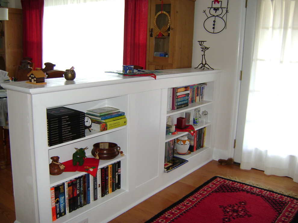 Bild på ett mellanstort vintage vardagsrum, med ett bibliotek, vita väggar, ljust trägolv och brunt golv