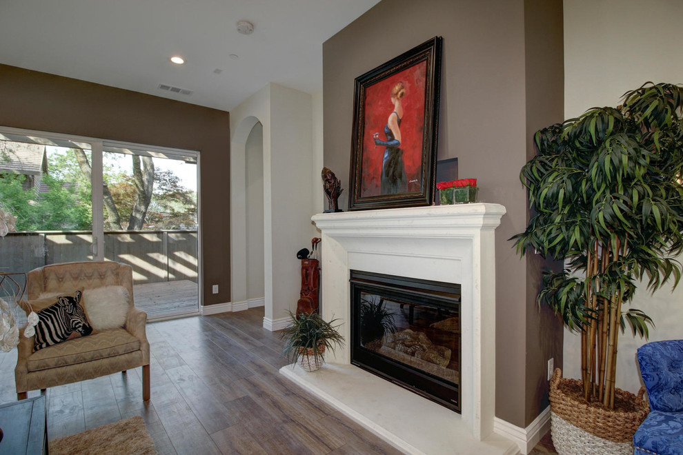 Example of a mid-sized classic formal and open concept laminate floor and brown floor living room design in Sacramento with beige walls, a standard fireplace and a wood fireplace surround