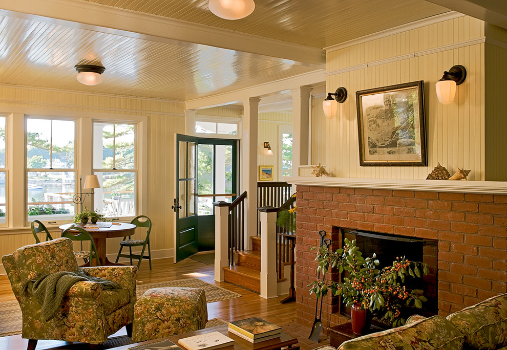 This is an example of a traditional living room in Portland Maine with yellow walls, a standard fireplace and a brick fireplace surround.