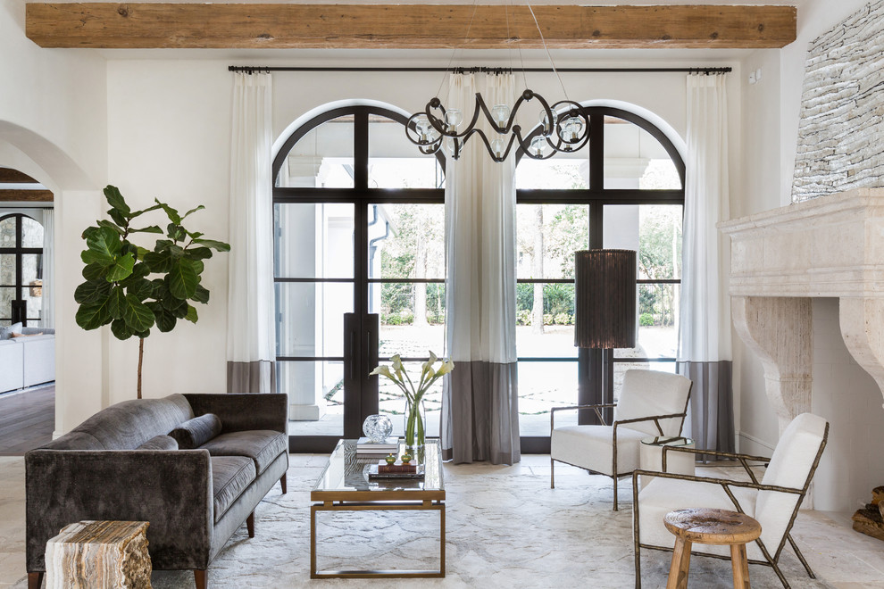 Esempio di un soggiorno mediterraneo con sala formale, pareti bianche, camino classico, cornice del camino in pietra e pavimento beige